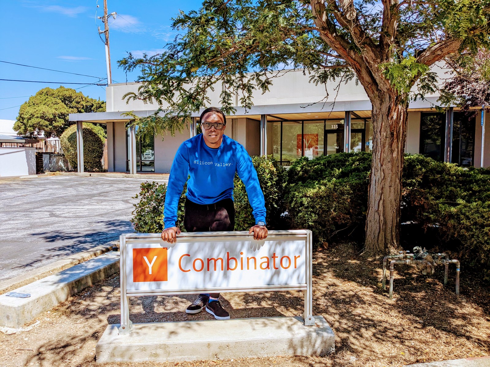 BW Simiyu in a blue Silicon Valley sweatshirt beside the Y Combinator sign