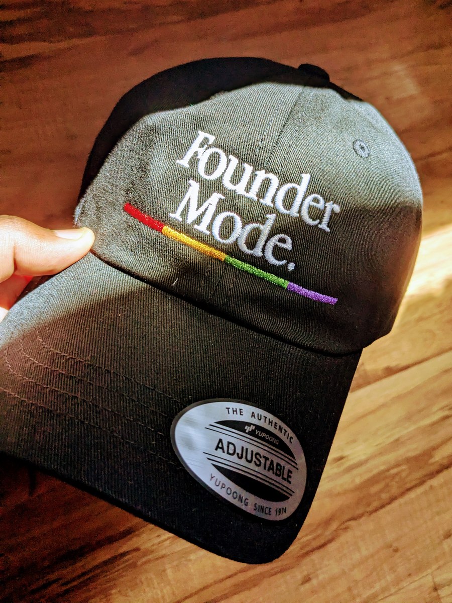 A Founder Mode cap held in hand, with colorful embroidery