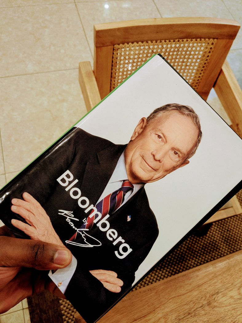 My copy of Bloomberg by Bloomberg held over a woven wooden chair
